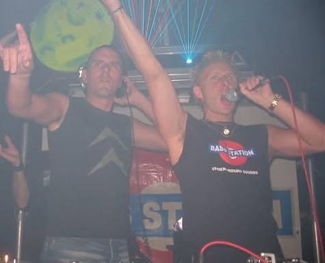 Old photograph of Jason Midro on stage with a microphone in a Bass Station shirt