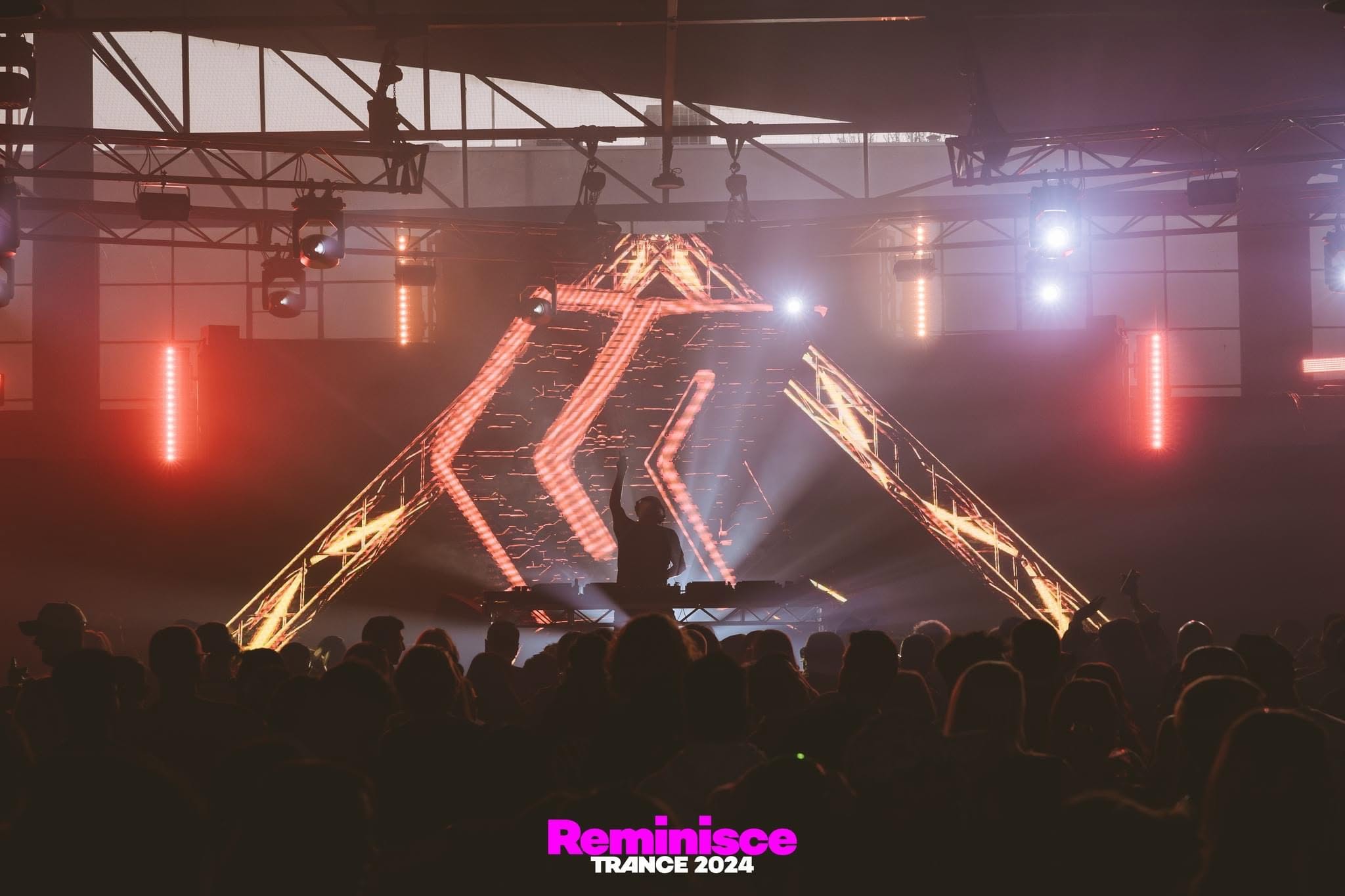 Jason Midro performing beneath a large illuminated triangular truss structure